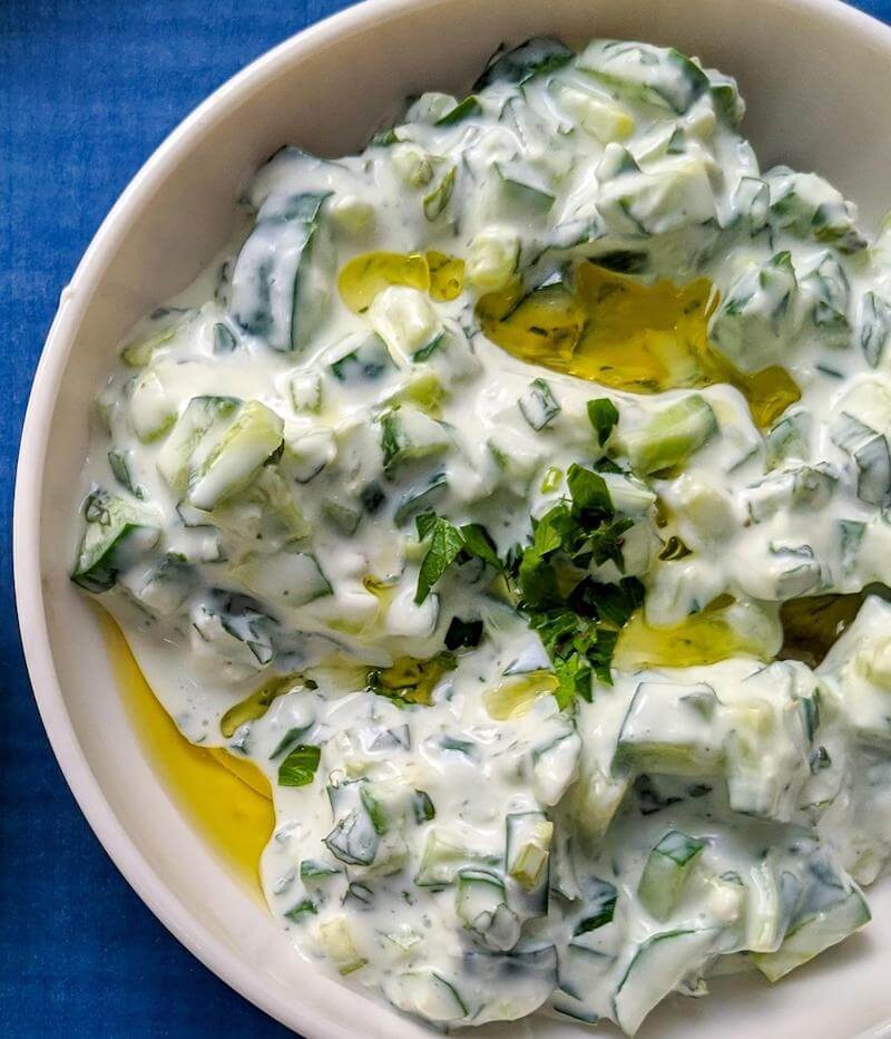There are different variations of tzatziki sauce.  One calls for drizzling olive oil over the tzatziki as a garnish with more fresh herbs.   This one is yogurt based.