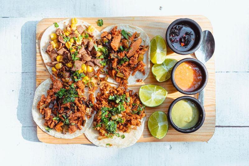 Tacos Al Pastor featuring marinated pork, onions, corn, fresh cilantro, homemade sauces and worm salt