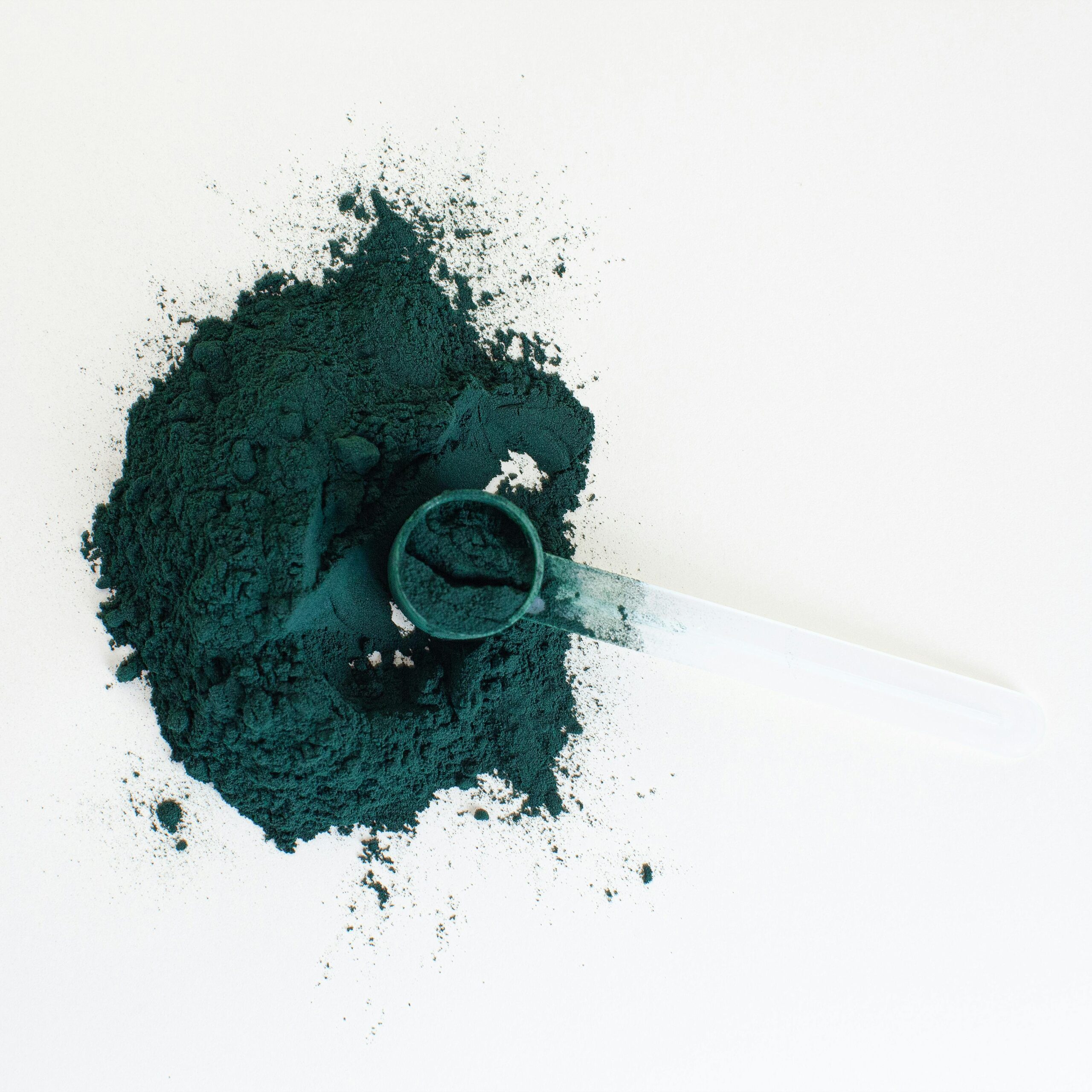 Chlorella for heavy metal detox shown as green algae powder with a wooden scooper