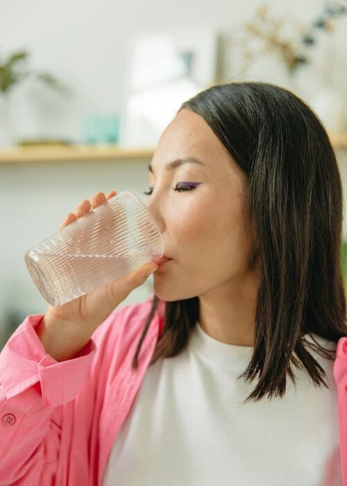 woman drinking morning detox water as part of wellness routine