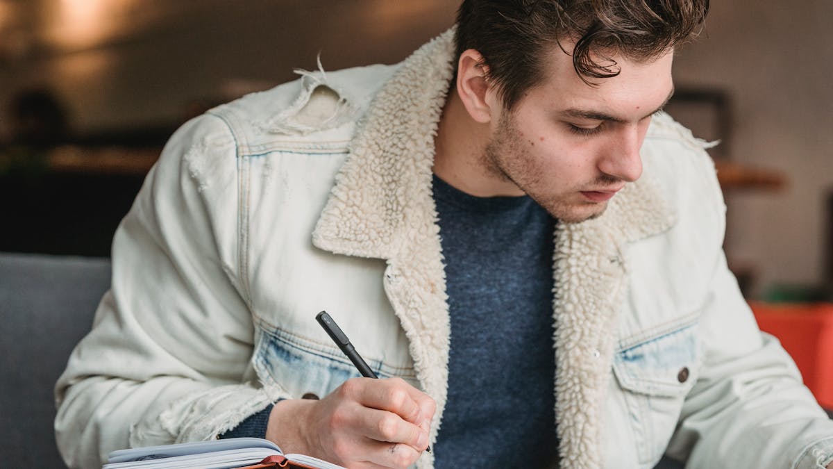 Paper journal and pen on a wooden table with morning coffee, representing a dopamine detox reset