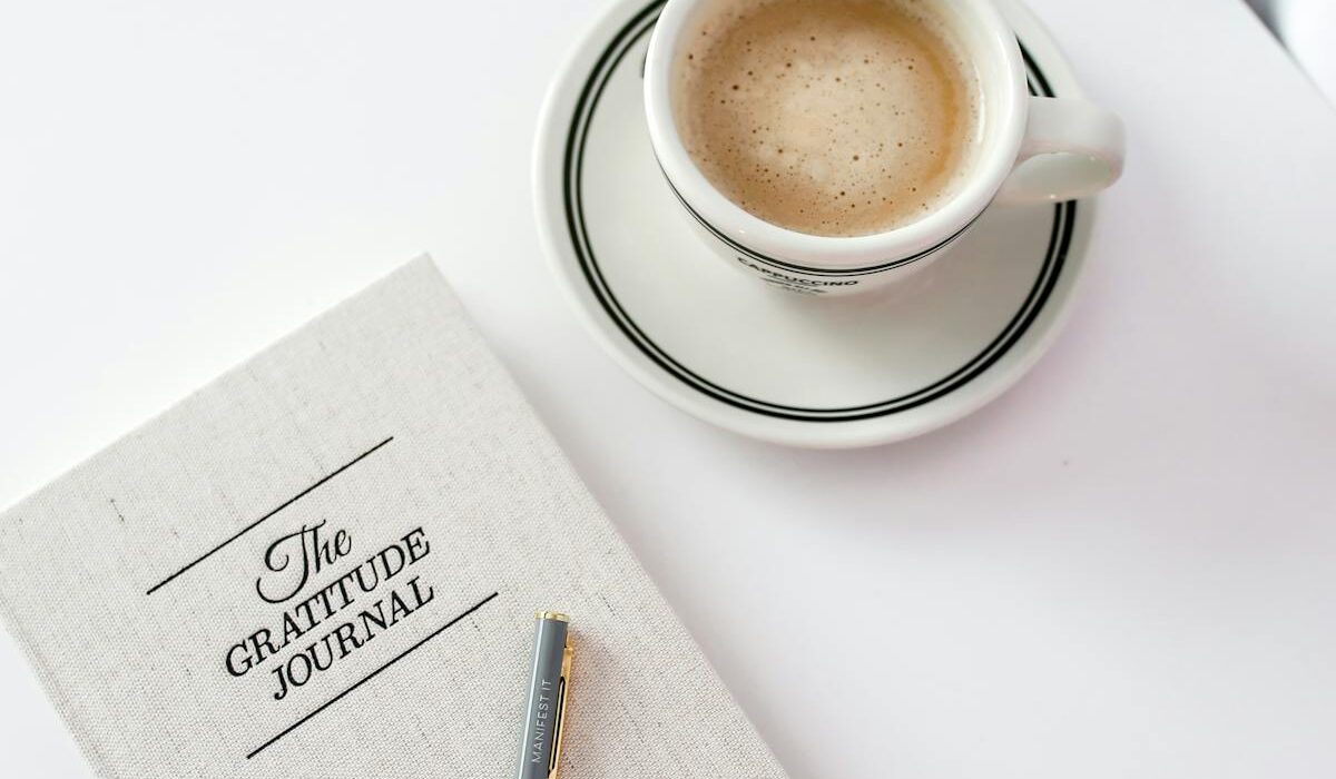 Gratitude journal beside coffee for mental health morning routine