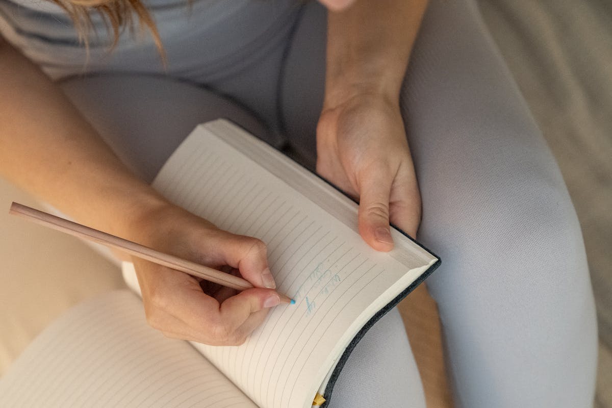 Hands writing in notebook for daily gratitude journaling practice