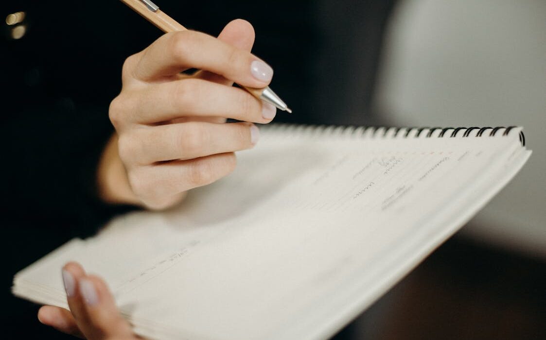 Person writing in a journal at a desk for reverse to-do list