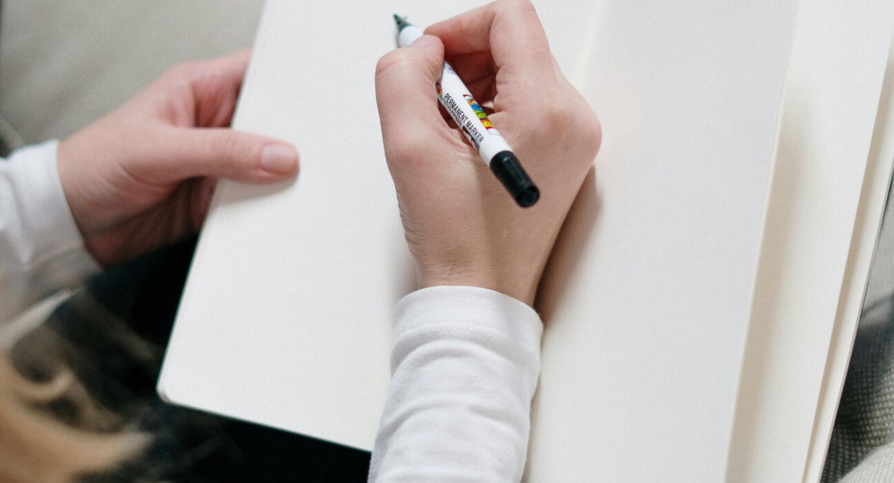 Top view of a woman writing in an open blank journal for morning pages