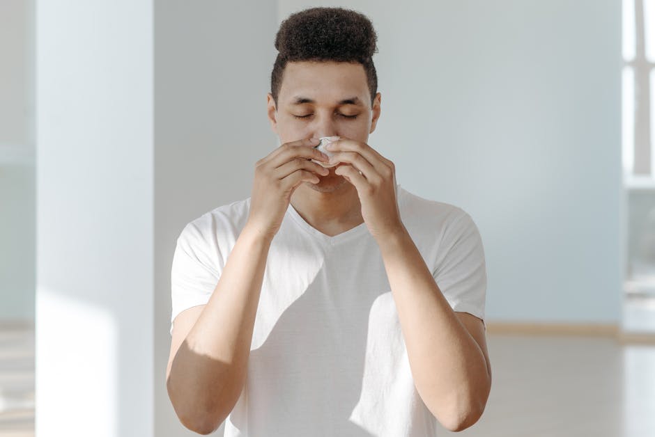 A man sneezing into a tissue, representing seasonal allergy symptoms.