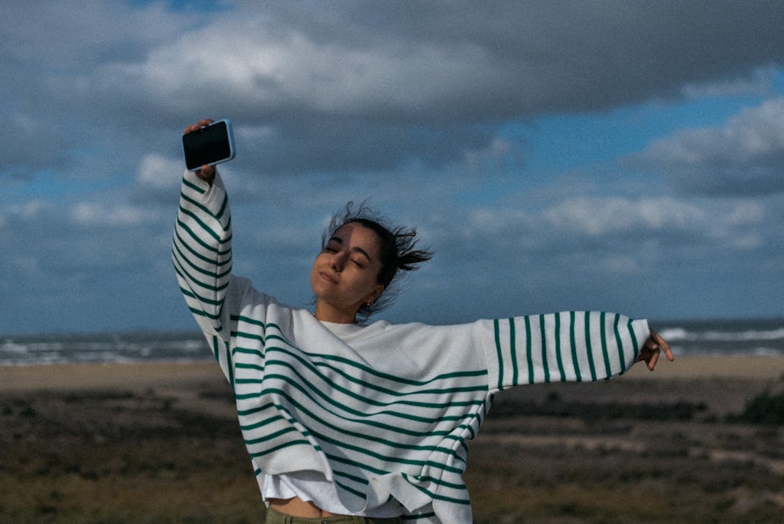 Woman standing on beach with phone practicing digital detox for mental health