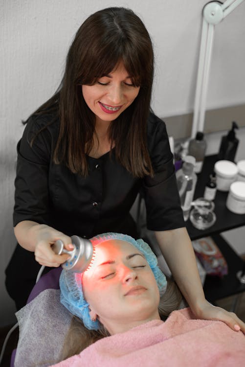 Woman having a facial treatment with red light therapy at home for beginners