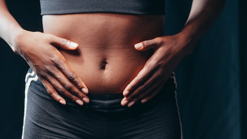 woman placing hands on abdomen where castor oil pack is applied at home