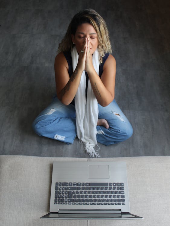 Woman meditating in front of laptop for digital detox and mindfulness