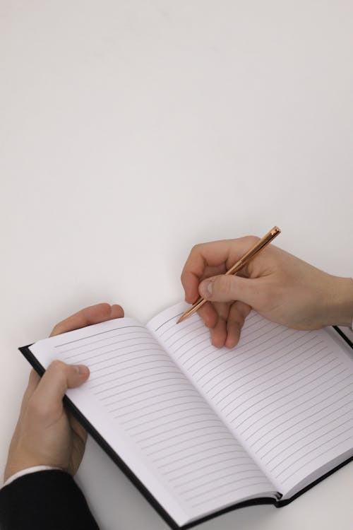 Person writing habit tracking notes in a notebook