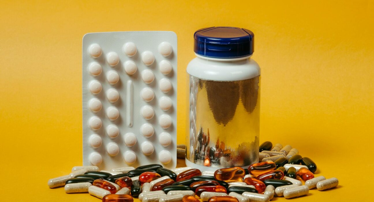 Magnesium glycinate with vitamin D3 K2 and B6 cofactor bottles on a wooden tray with water and spinach