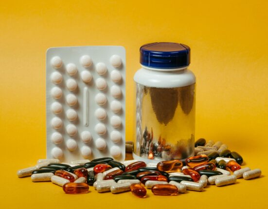 Magnesium glycinate with vitamin D3 K2 and B6 cofactor bottles on a wooden tray with water and spinach