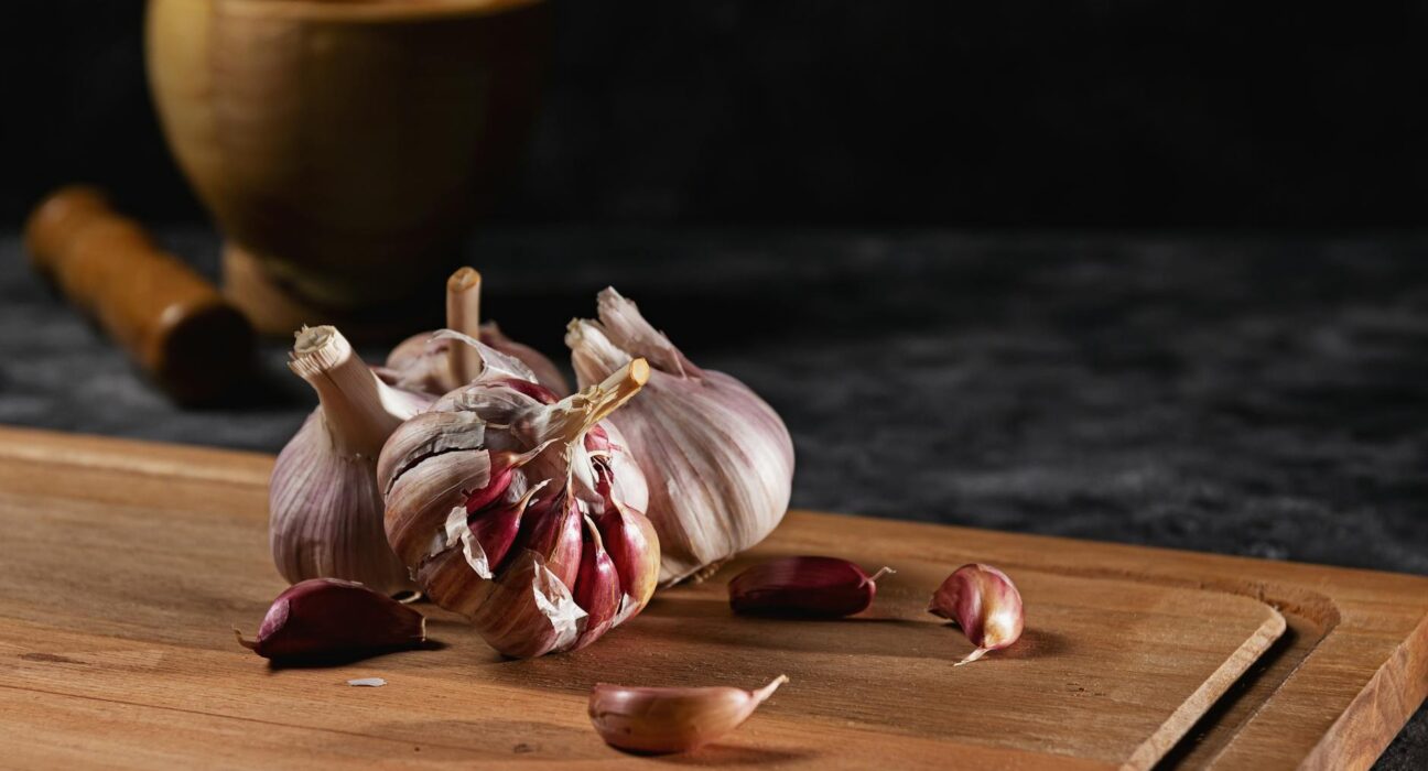 Anti-parasitic foods on a wooden cutting board — pumpkin seeds, garlic, papaya seeds, cloves