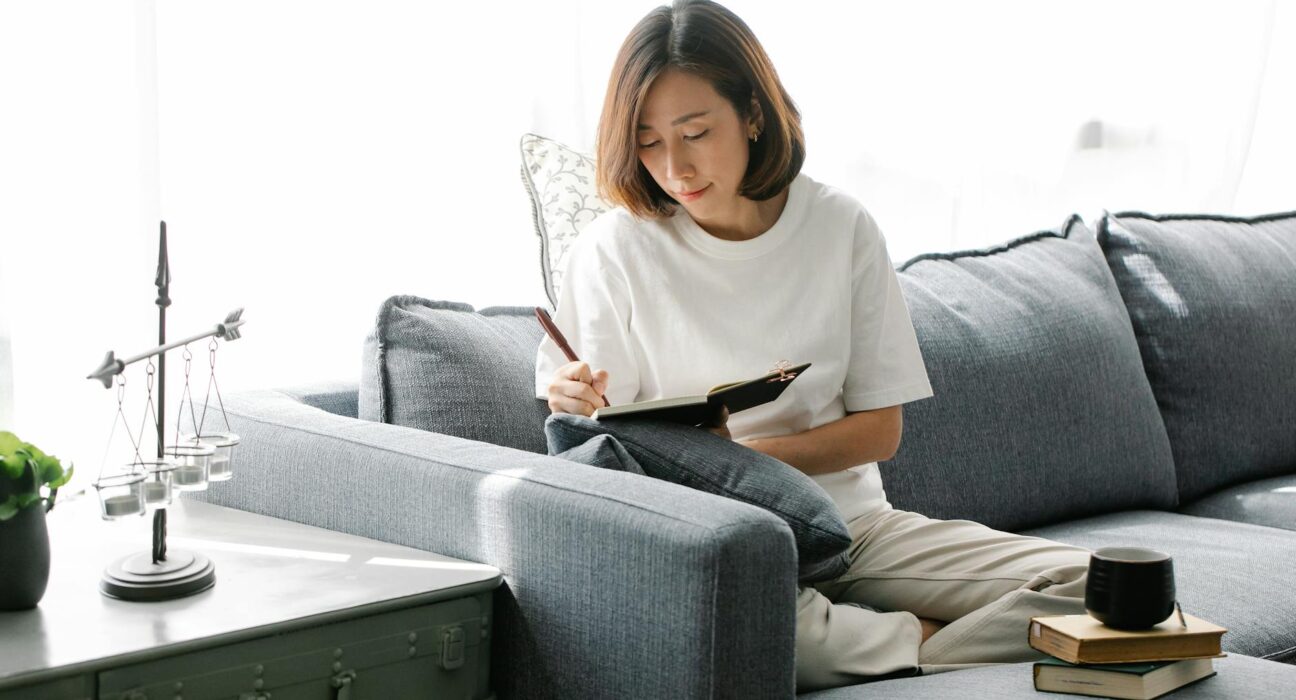 Woman calm and reflective with a journal in a peaceful bright living room