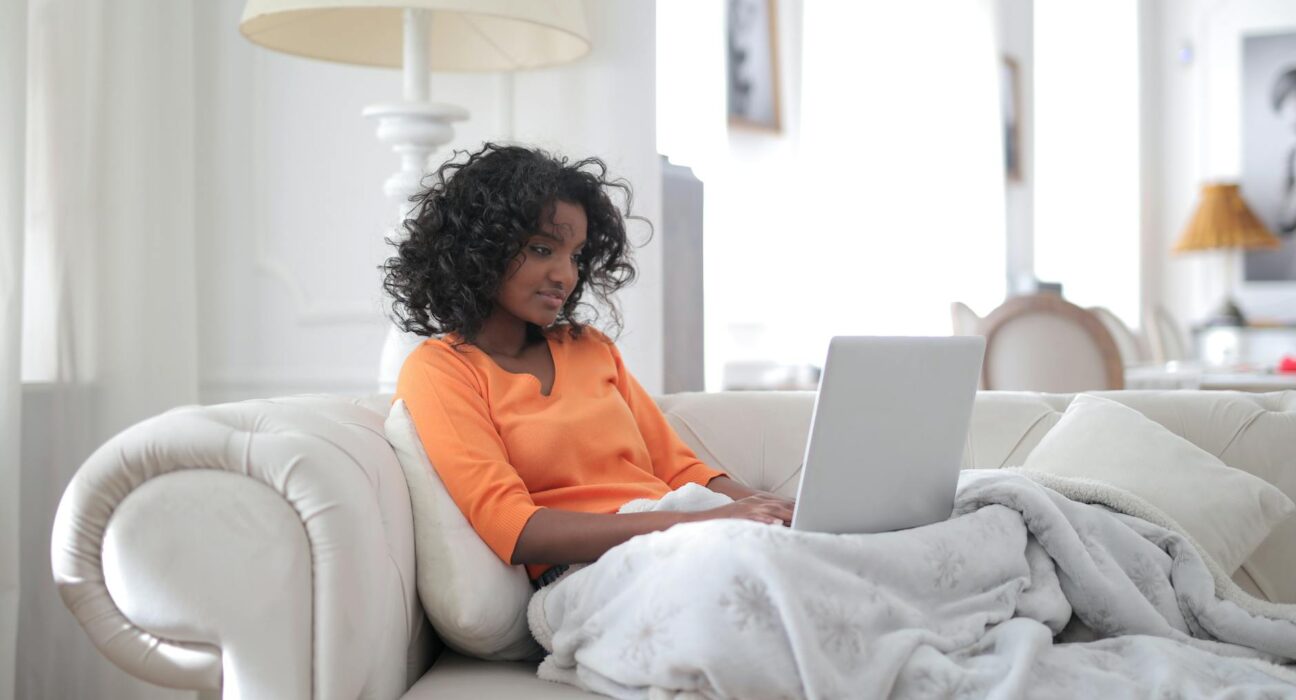 Woman reflective on a couch with a warm drink in a sunlit living room