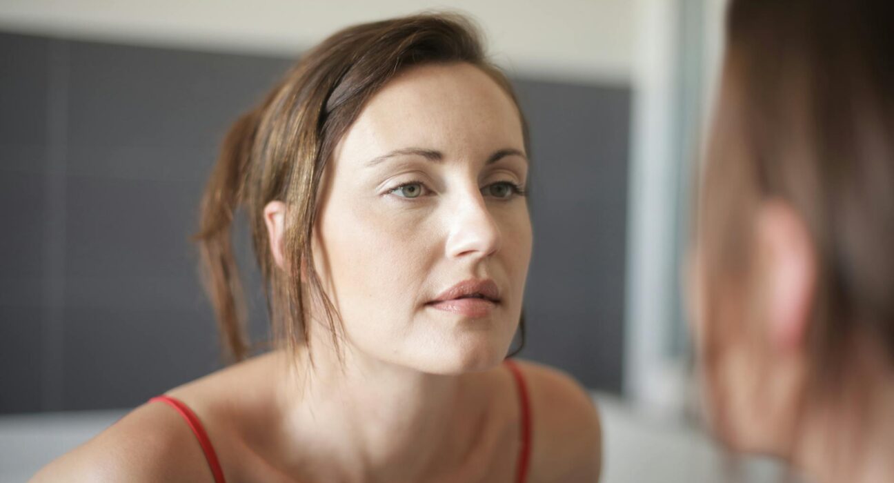 Woman checking her tired-looking face in the bathroom mirror