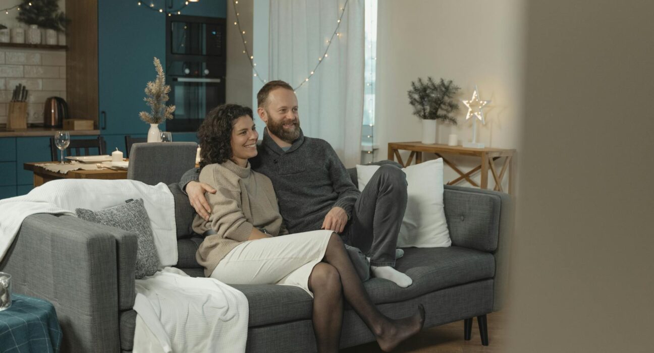 Couple resting together on the couch with the woman looking tired but supported