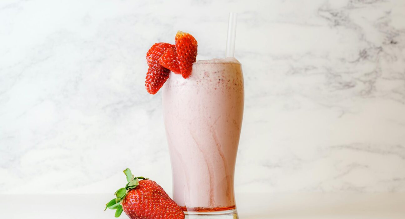Collagen smoothie with acerola cherries and unflavored collagen peptides powder on a marble counter