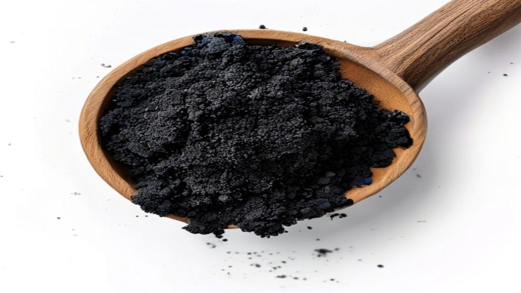 activated charcoal for detox powder in wooden spoon