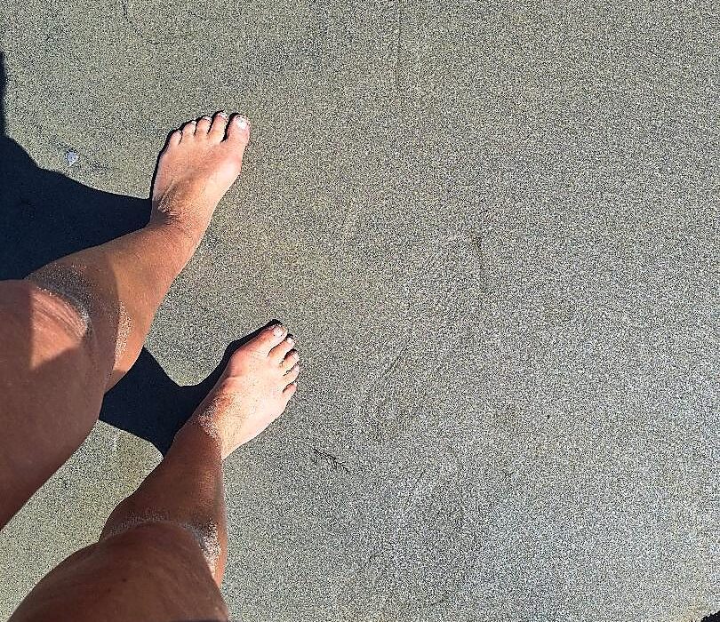 Bare feet grounding on sand alongside food grade diatomaceous earth for detox