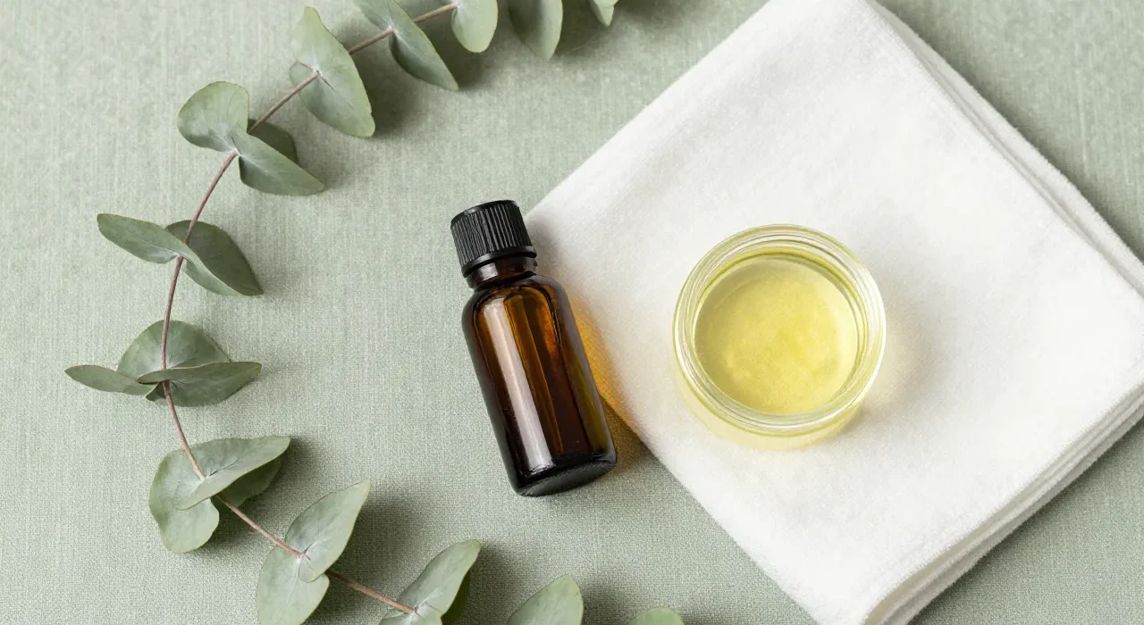 Editorial flat lay of foot care wellness essentials: tea tree oil, coconut oil, eucalyptus