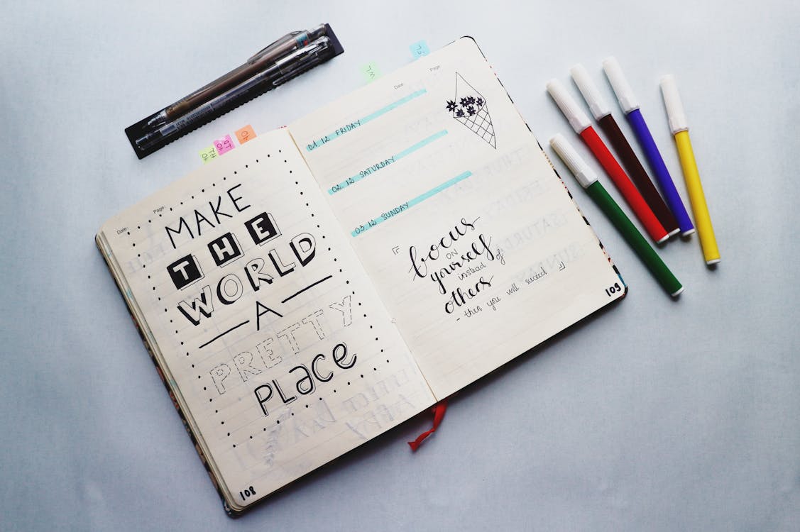 Open bullet journal with markers for five minute journal vs bullet journal planning style