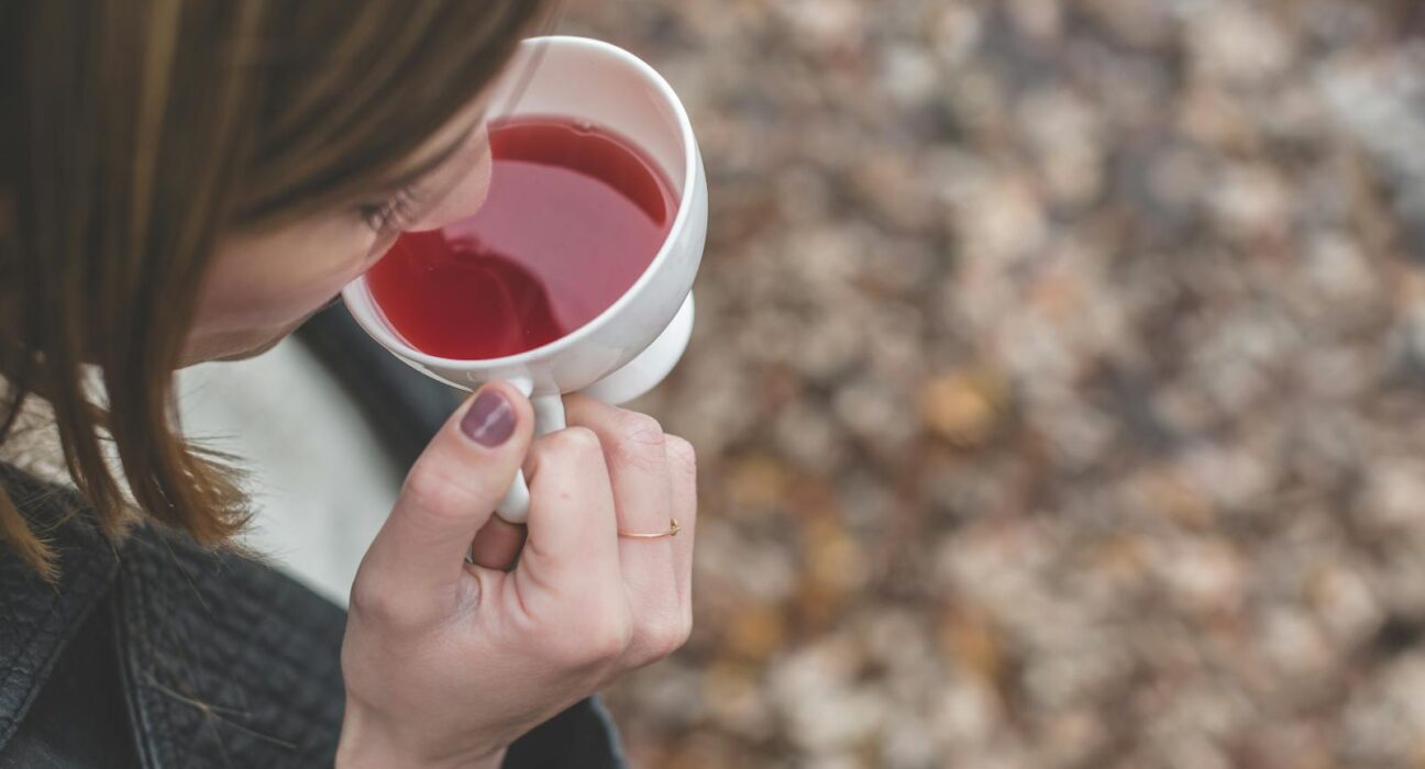 Woman sipping warm burdock root tea outdoors