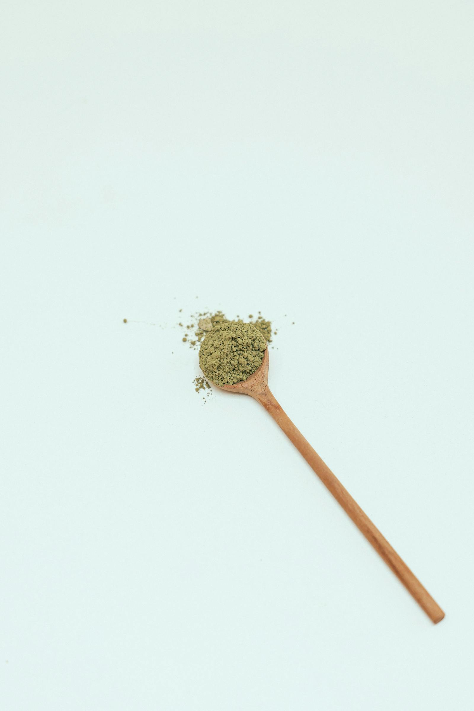 Heaping wooden spoon of bright green chlorella powder showing daily dose