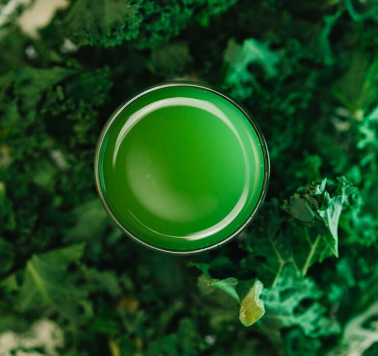 Chlorophyll water benefits for skin in a green drink surrounded by fresh kale