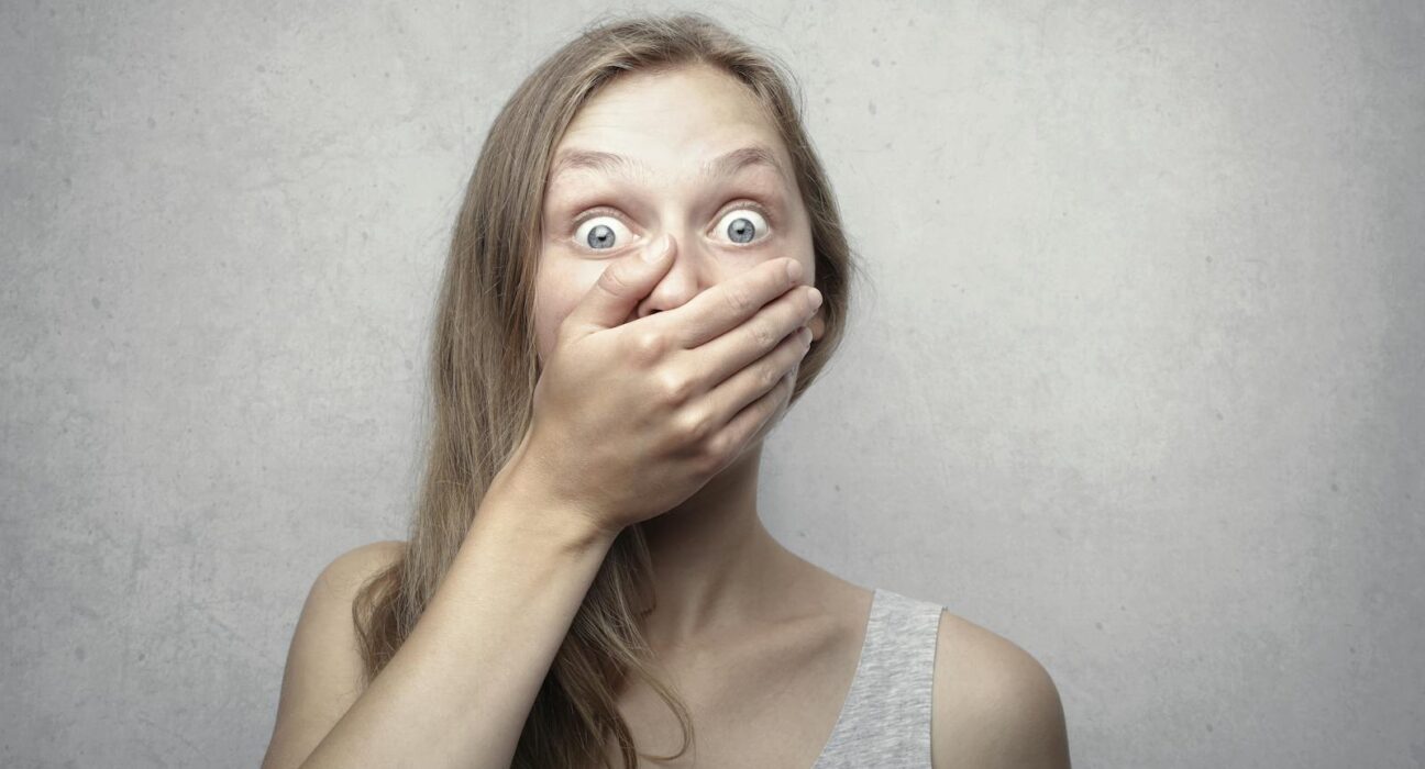 Woman covering her mouth, conflicted between coughing freely and being judged as sick