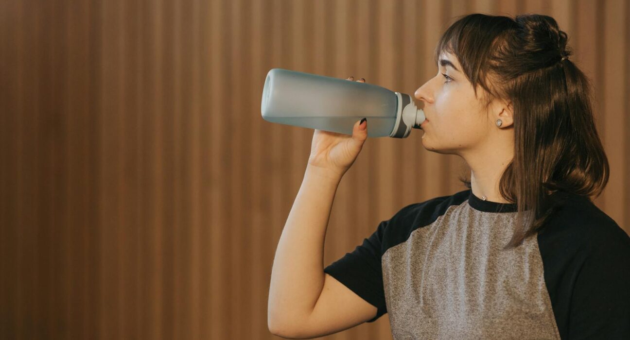 Woman drinking water during anesthesia detox recovery after dental surgery