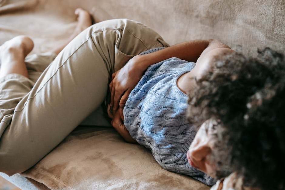 person with stomach pain on couch indicating possible food poisoning vs stomach bug