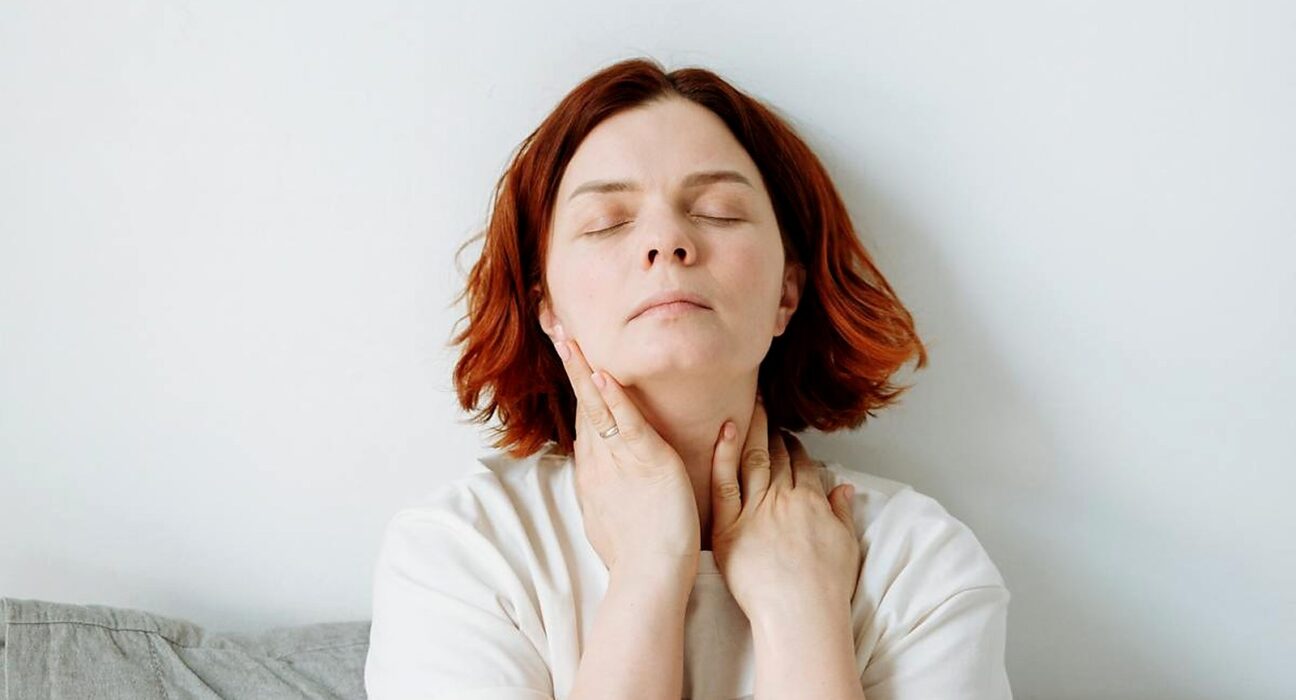 Castor oil pack for thyroid serene woman with hands on her throat in peaceful daily ritual