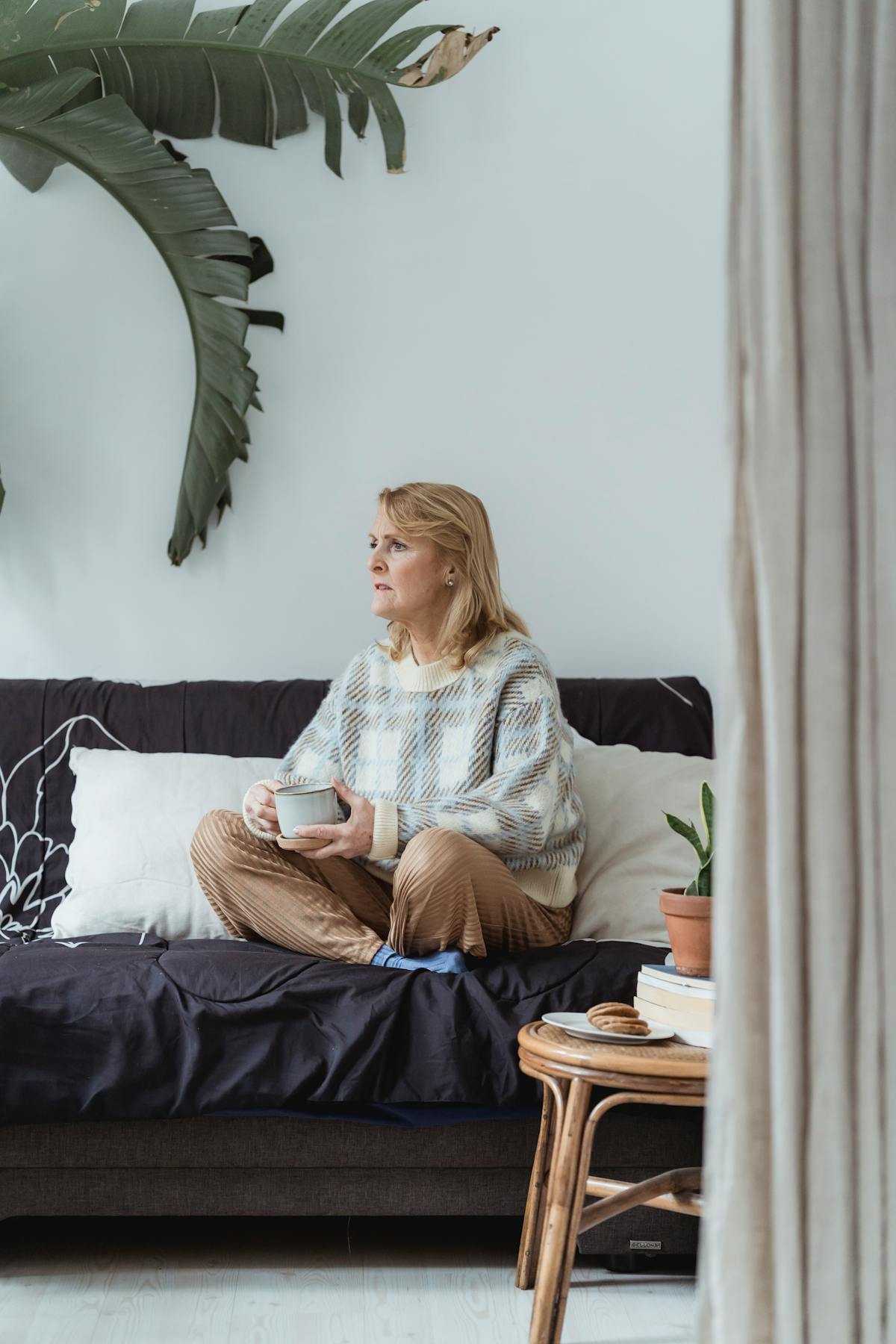 Woman holding warm drink in cozy living room after castor oil pack for thyroid session