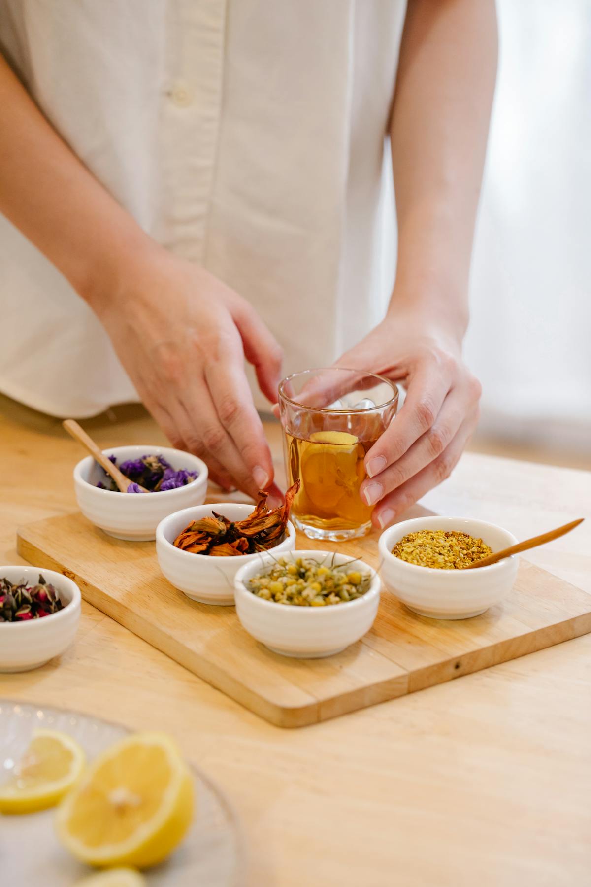 Hands arranging fresh herbs and lemon for parasite cleanse at home tea