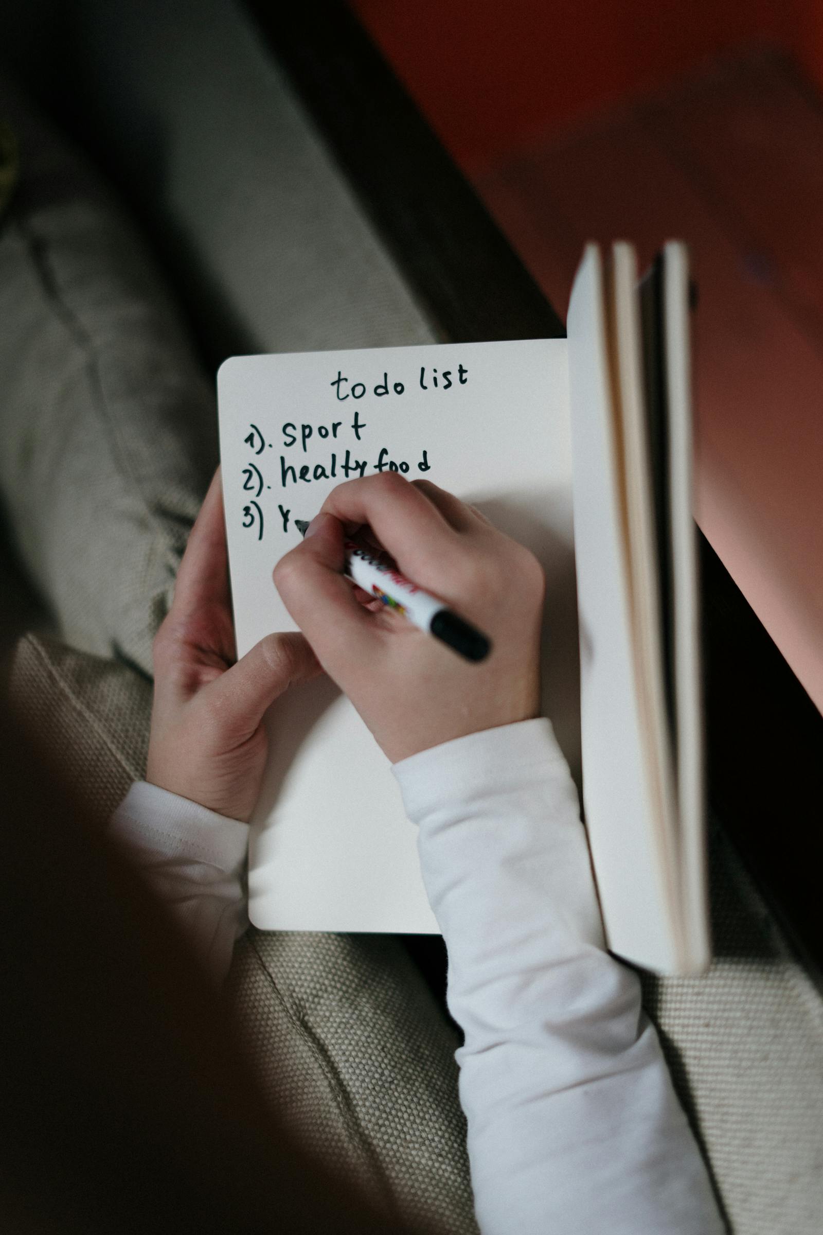 Person writing six tasks the night before for the Ivy Lee method for daily productivity