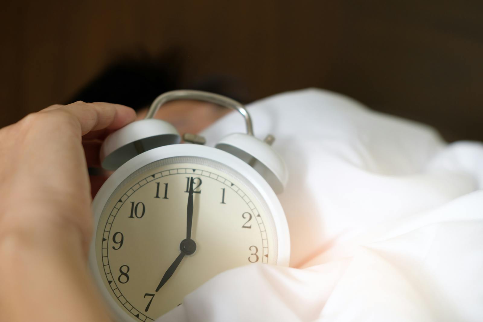 Hand reaching for the morning alarm clock to start the five second rule