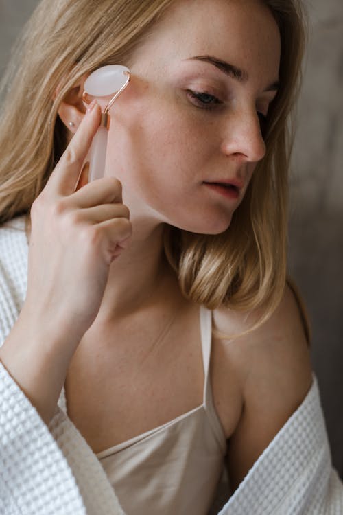 Woman using a face massage tool for terahertz wand vs rose quartz roller daily skincare