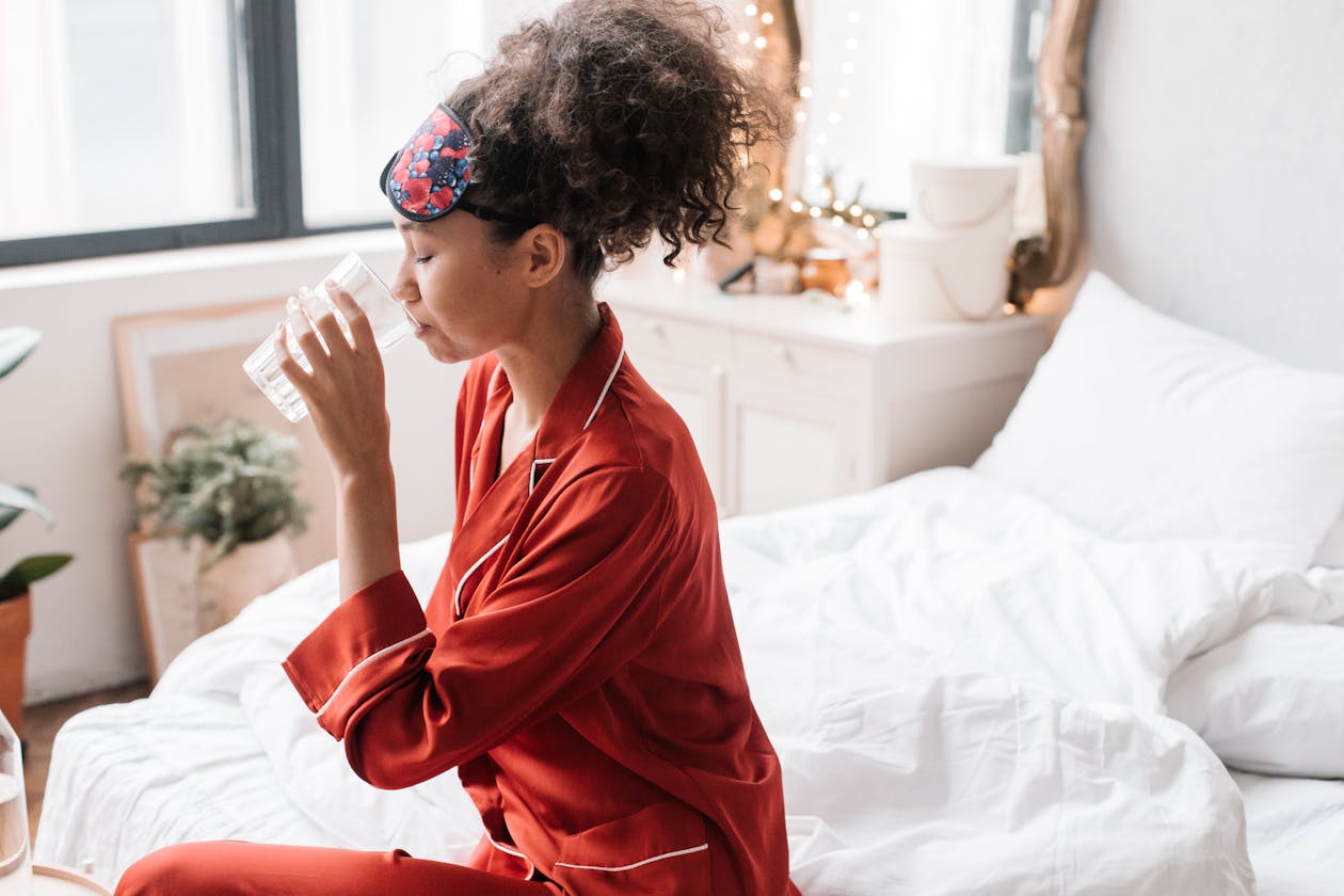 woman in pajamas drinking a glass of water as part of her morning energy routine