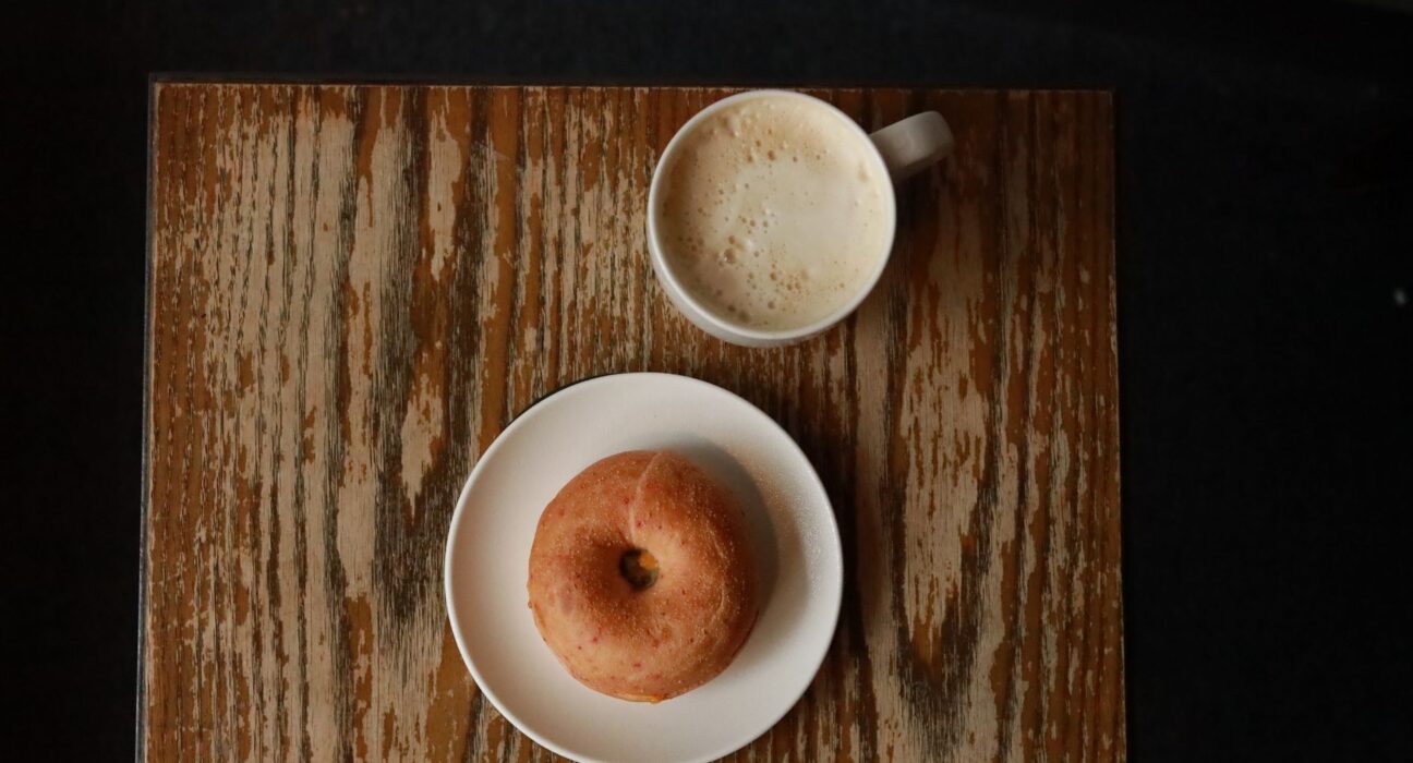 Top-down view of a donut and cup of coffee on a rustic wooden table, illustrating a typical Dunkin order