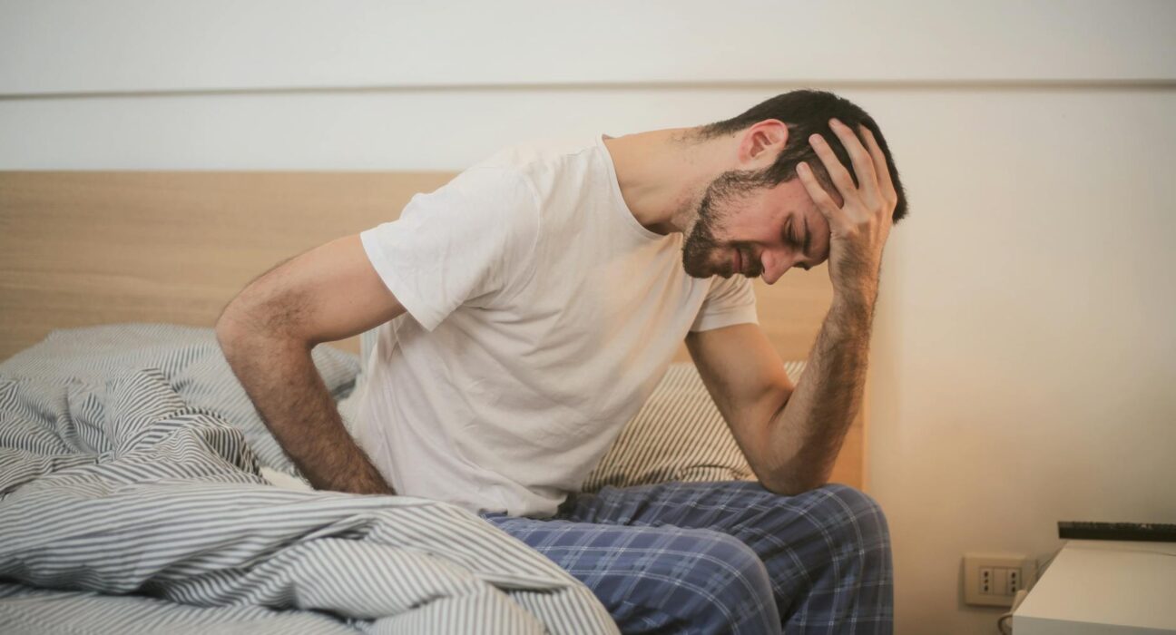 Tired woman sitting on a sofa during a heavy metal detox protocol experiencing Herxheimer reaction symptoms