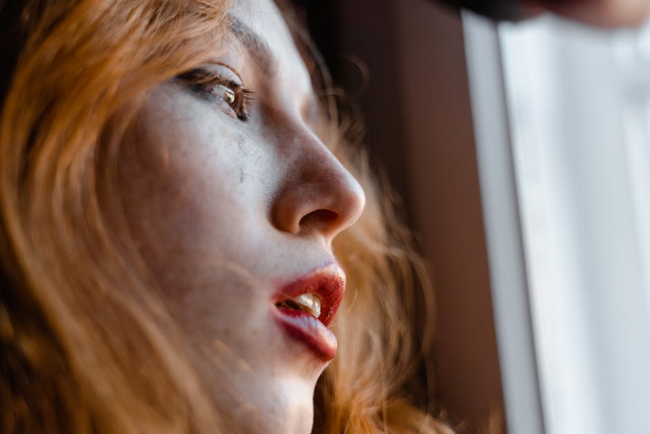 Adult standing by a window practicing nervous-system grounding techniques in a public setting